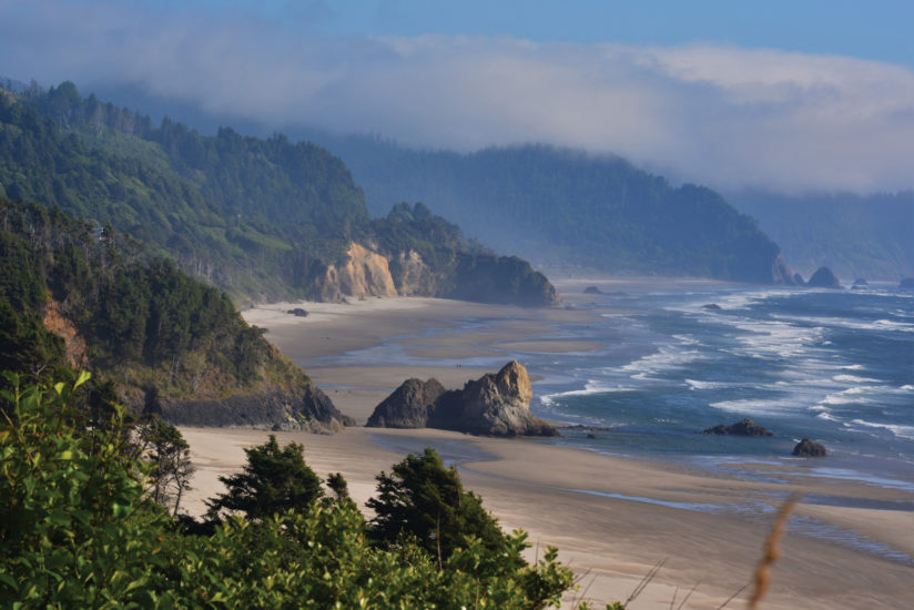 The Oregon coast on a mostly sunny day with sand, rocks, and gentle waves delivering a welcoming vibe.